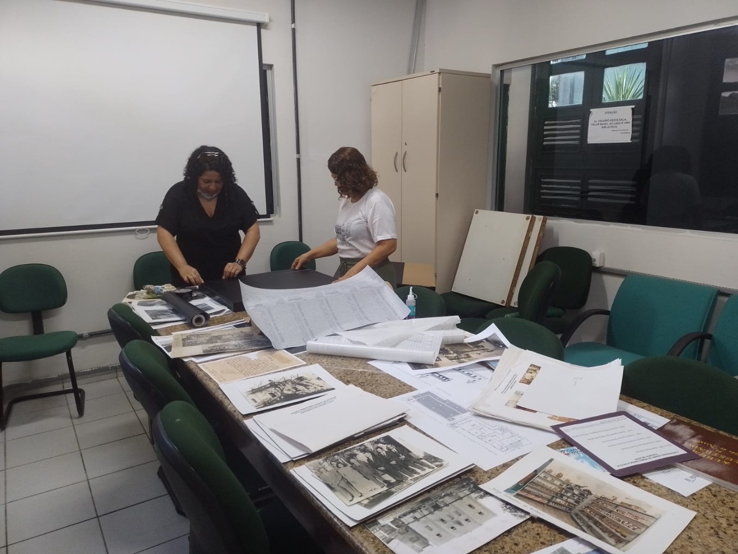 Bibliotecária Ana Caroline e arquiteta e professora Ariadne Aguiar preparando peças da exposição sobre história do Campus Satuba