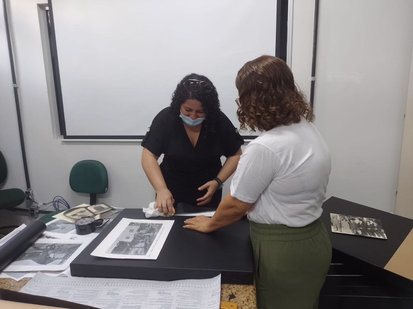 Bibliotecária Ana Caroline e arquiteta e professora Ariadne Aguiar preparando peças da exposição sobre história do Campus Satuba