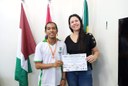 Professora Norma Amorim, coordenadora da OBA no Campus, entrega certificado e medalha de bronze ao aluno Murilo Pedro Pereira